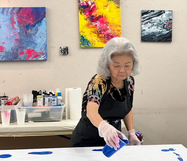 Ming Franz pouring colour on canvas for a new painting in her studio